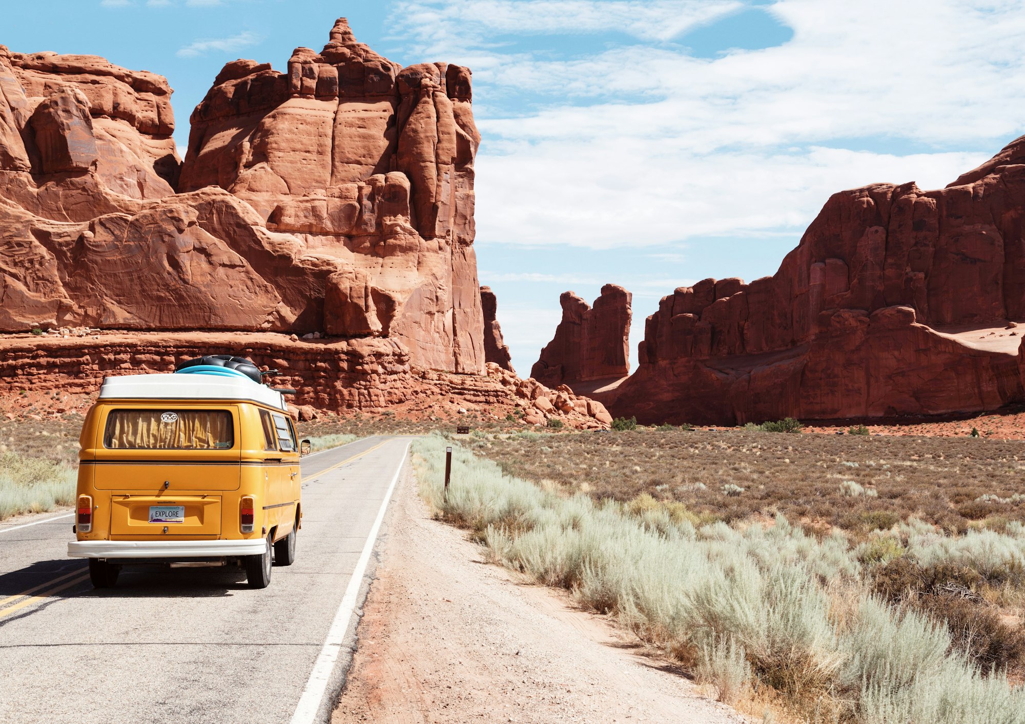 A yellow van on an open desert highway in the American West